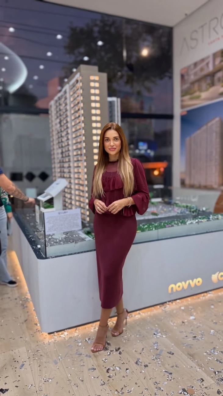 Betina comemorando uma venda em frente à maquete